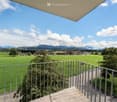 A balcony with a metal railing and a view of a green meadow and mountains