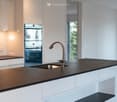 Modern kitchen with white cabinets, black countertop, stainless steel sink, and a sleek faucet