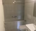 Bathroom with bathtub, toilet, sink and mirror, fully tiled walls and floor
