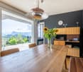 wooden dining table, wooden chairs, shelf with objects, large window with view