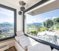 large windows, couch, cushions, table with chairs, pendant lamps, radiator, view of the mountains