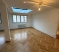 Wooden floor, white walls, central ceiling light, glass window, radiator, skylight window