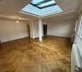 open room, wooden floor, skylight, white walls, three doors, radiators