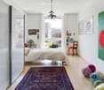 bedroom with bed, rug, chair, windows, wall art