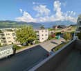 Apartment balcony with view of town, mountains, river, and lake