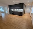 empty room, wooden floor, white walls, modern black kitchen cabinets, integrated sink, oven, window, double doors