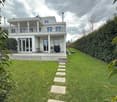 modern house, white exterior, large windows, balcony, well-kept garden, hedges