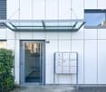 White building, glass door, glass canopy, mailbox, ivy plant