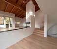modern interior with wooden floor, white walls, large windows, fireplace, stairs, exposed wooden ceiling