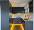 modern kitchen with gray cabinets, wooden floor, integrated lighting, black faucet