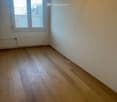 Empty room, wooden floor, large windows, white walls, radiator, power outlet