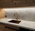 kitchen sink with faucet, marble countertop, wooden cabinetry, electrical outlet