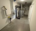 Utility room with pipes, heating system, and water tank.