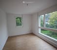 empty room with white walls, wooden floors, two large windows