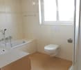 Bathroom with bathtub, shower stall, toilet, sink and tiled flooring.