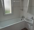 A bathtub, sink, shower, and mirror. Wooden flooring.