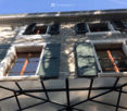 stone building, multiple windows, green shutters, terrace