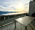 A balcony with a view of the lake and mountains, metal table and fence.