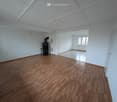 Empty room with wooden floors, white walls, fireplace, window