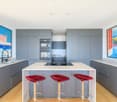 modern gray kitchen, large island, red stools, double oven, granite countertops