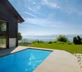 house with a view, swimming pool, green lawn, rocky border, mountains in the distance, clear sky