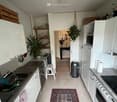 kitchen: sink, dishwasher, gas stove, cabinets, microwave, refrigerator, trash bin, plant, carpet