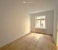 Empty room, wooden floor, white walls, large window, radiator under the window