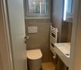 Small bathroom with window, white toilet, white sink, wall-mounted towel rack