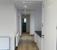 Wooden floor, white walls, radiators, hallway leading to rooms