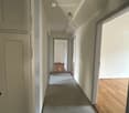 Empty corridor, wooden floors, white walls, doors, ceiling light