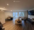 living room, wooden floor, dining table, chairs, couch, TV, balcony with city view