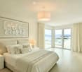 white king size bed, bedside tables with lamps, large framed artwork, sliding doors, balcony, panoramic view