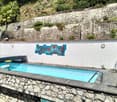 outdoor rectangular swimming pool with stonework and tiles, white wall, mural, wall lights, pool ladder