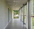 long hallway, gray walls, concrete floor, glass windows with white curtains, two rooms with doors on left side