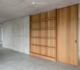 minimalistic room with a wooden wall-mounted bookcase, light gray floor, and white walls