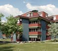 3 story building, blue and red facade, balconies, green roof, lawn, plants, trees