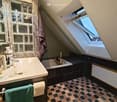 Bathroom with a bathtub, sink, mirror, skylight window, tiled floor