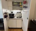 small kitchen with modern appliances and cabinetry, microwave, oven, refrigerator, sink, dishwasher, wine glasses