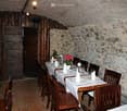 Stone walls, wooden ceiling, long dining table, wooden chairs, white tablecloths