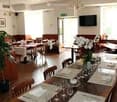 Dining tables with set up for dining, white cloths, glasses, cutlery, flowers in vase