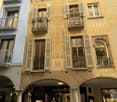 yellow facade with elaborate carvings, arched doorways, balconies, windows with shutters, store fronts