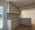 Modern kitchen, island, under cabinet lighting, balcony with railing, glass door to balcony