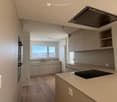 Kitchen with modern cabinets, built-in oven, dishwasher, and large windows.