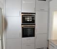 White cabinets, stainless steel handles, brown tiled floor, double oven, dishwasher, modern lighting