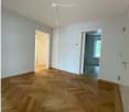 Empty room with wooden parquet flooring, white walls, and two doors leading to other rooms.