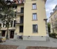 3 story yellow house, several windows, balcony, 2 doors