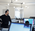 open office layout, white walls, ceiling lights, computer setup, desk, chair, man standing