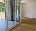 Empty room with wooden flooring and large glass sliding doors leading to an outdoor area.