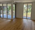 Empty room with light wooden flooring and large glass sliding doors leading to an outdoor area.
