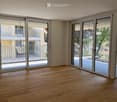Empty room with wooden flooring and large sliding glass doors leading to a balcony.